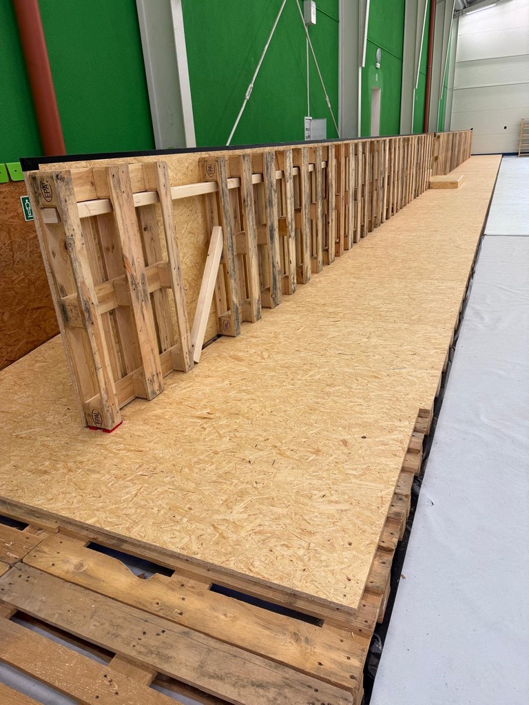 Lange Unterkonstruktion aus Holzpaletten am Rand der Arena Buštěhrad